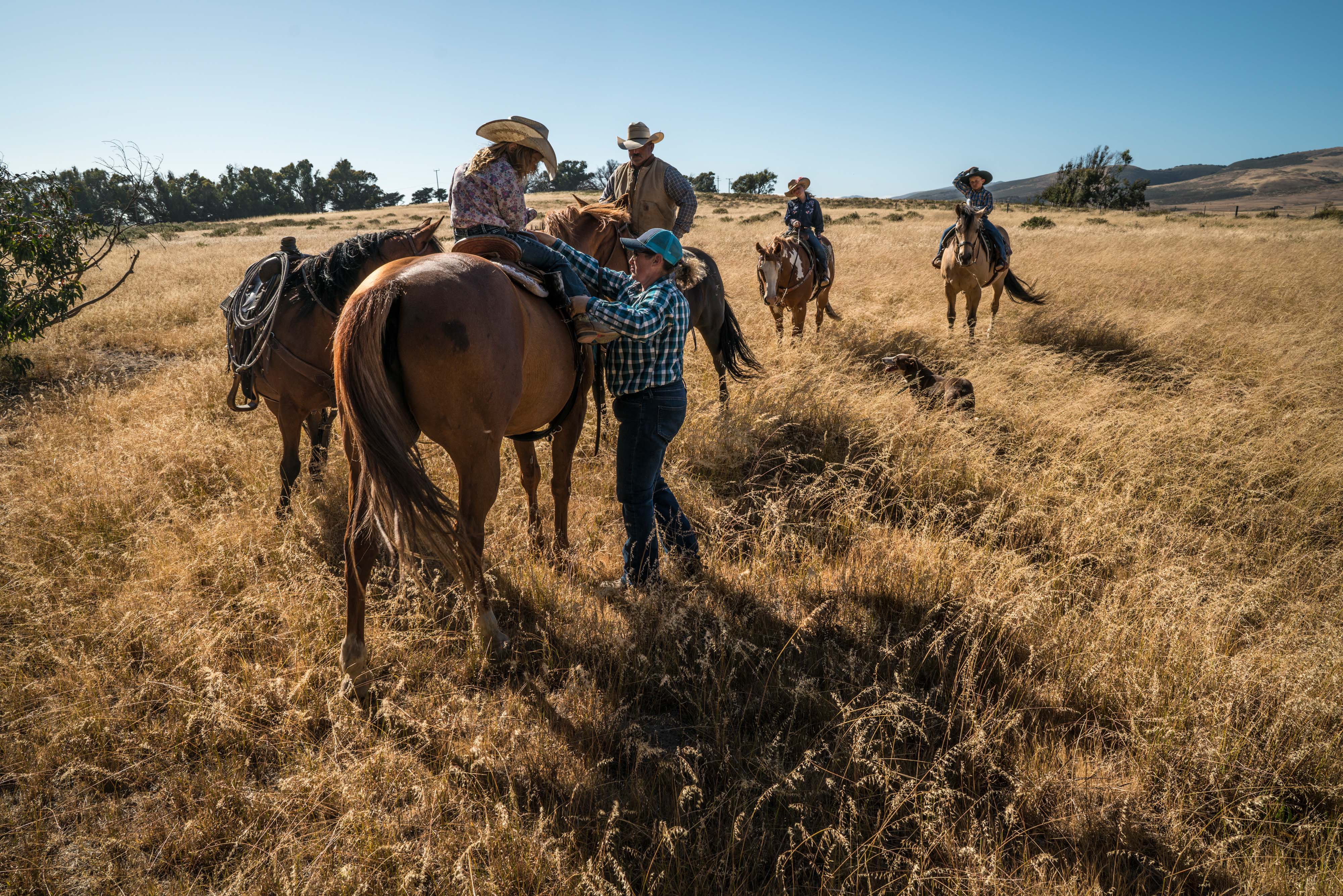 Una familia del rancho monta a caballo en una zona cubierta de hierba.