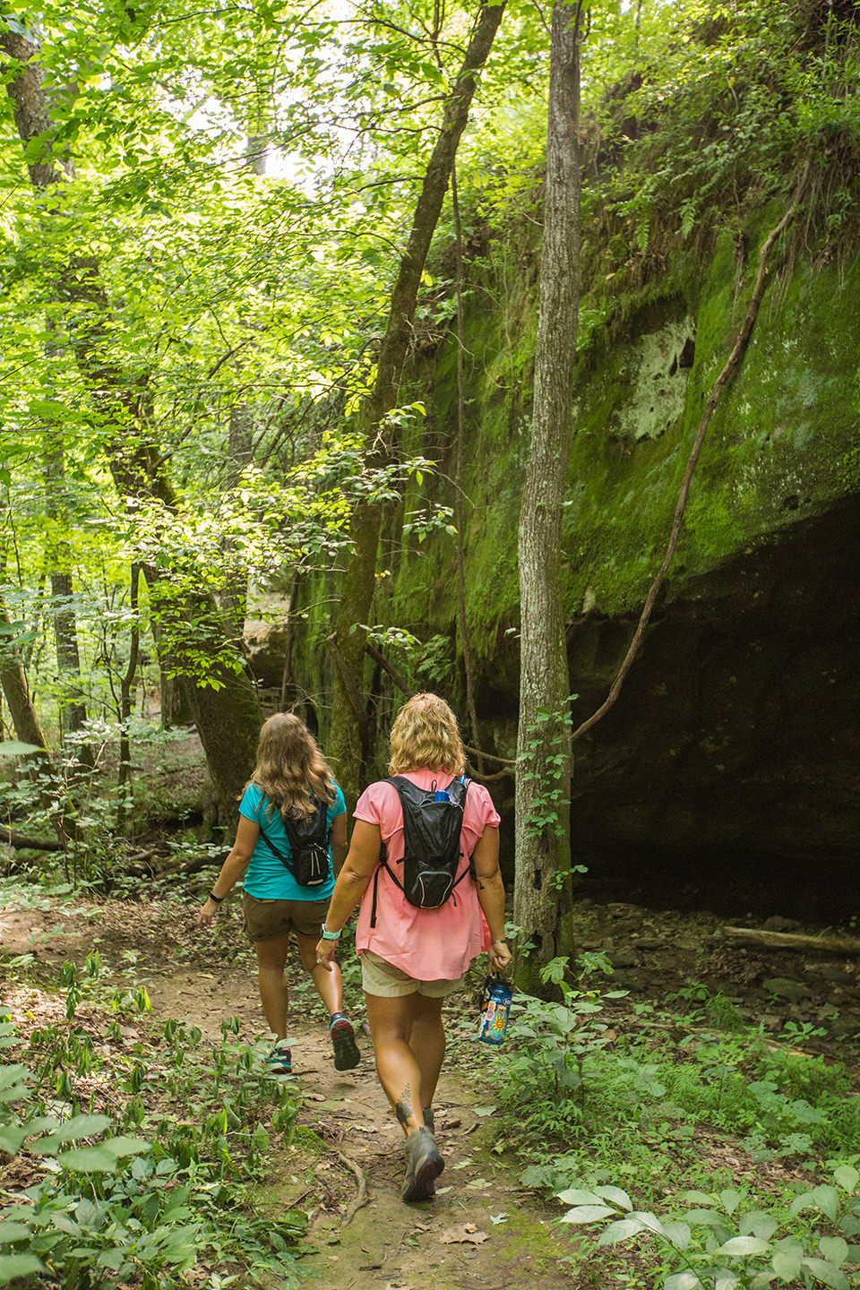 Two hikers walk past Mantle Rock.