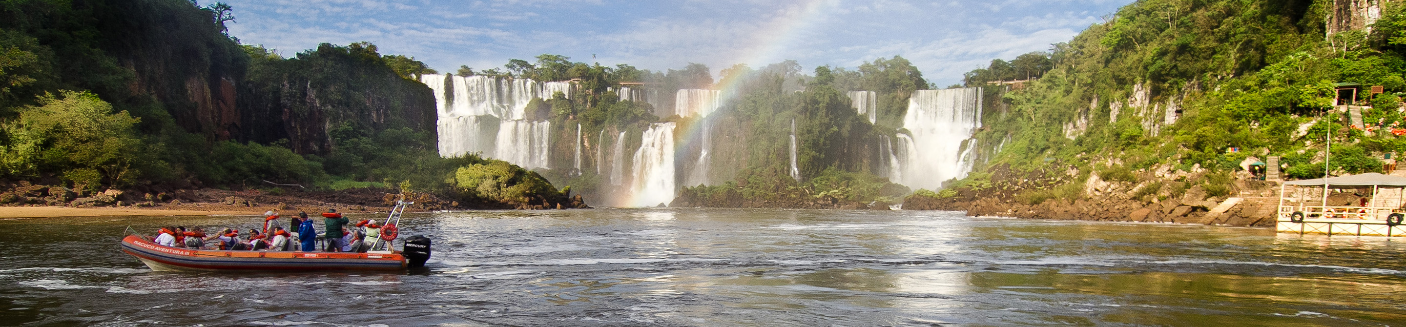 Tourists sit in a red motor boat at the based of Iguaçu