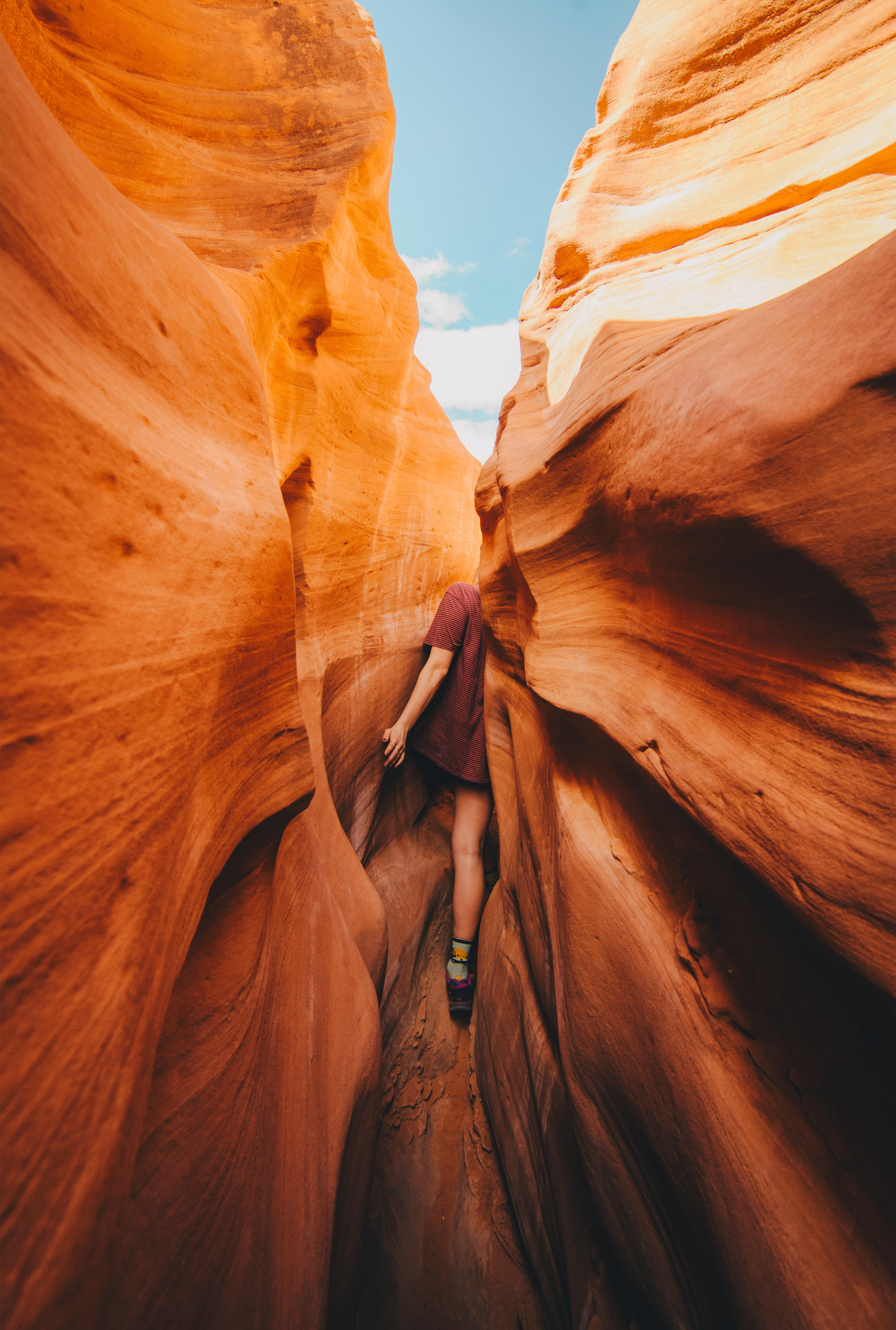 Woman squeezes through a narrow slot canyon in Escalante National Monument in Utah.