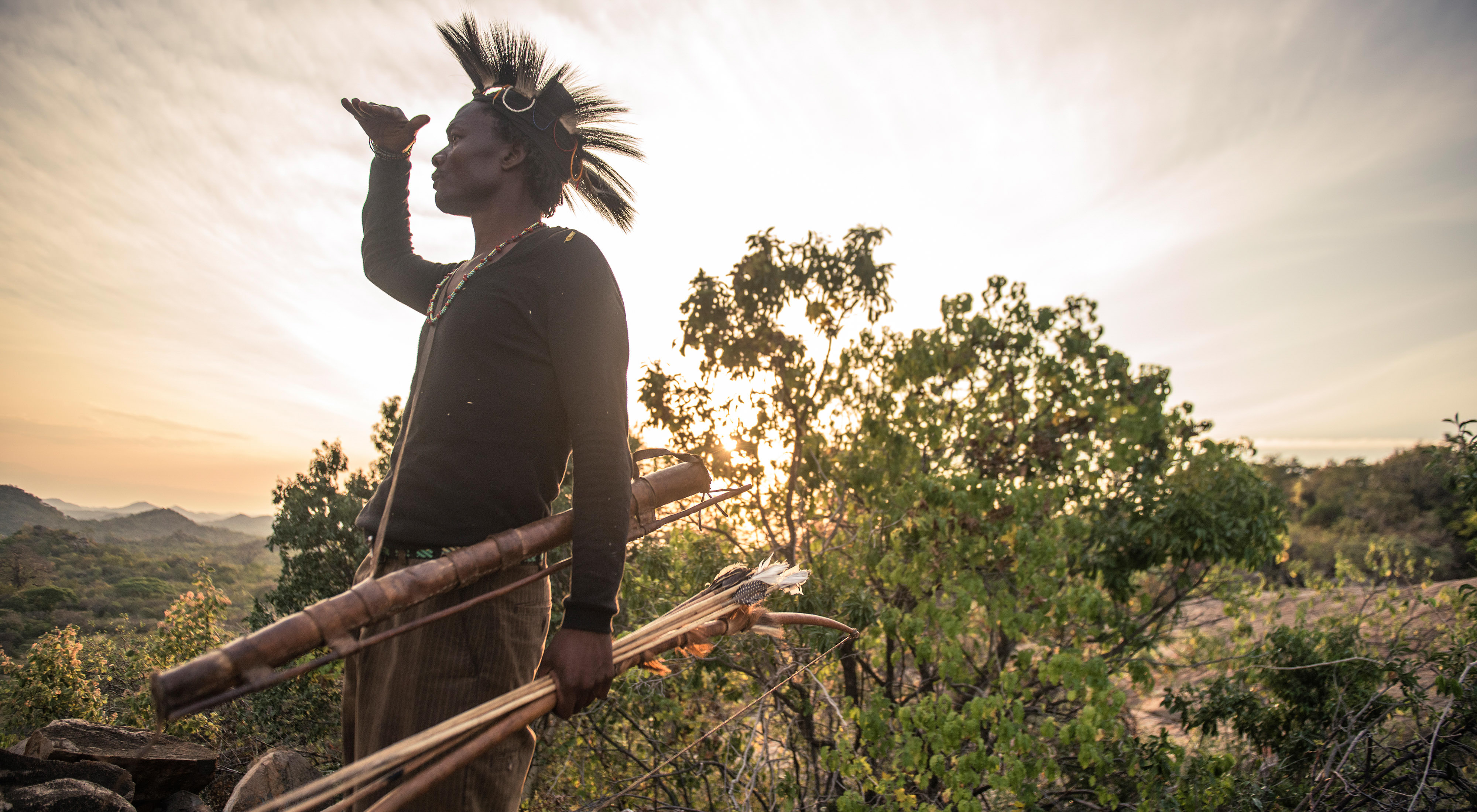 A hunter surveys a valley in Tanzania, looking for game