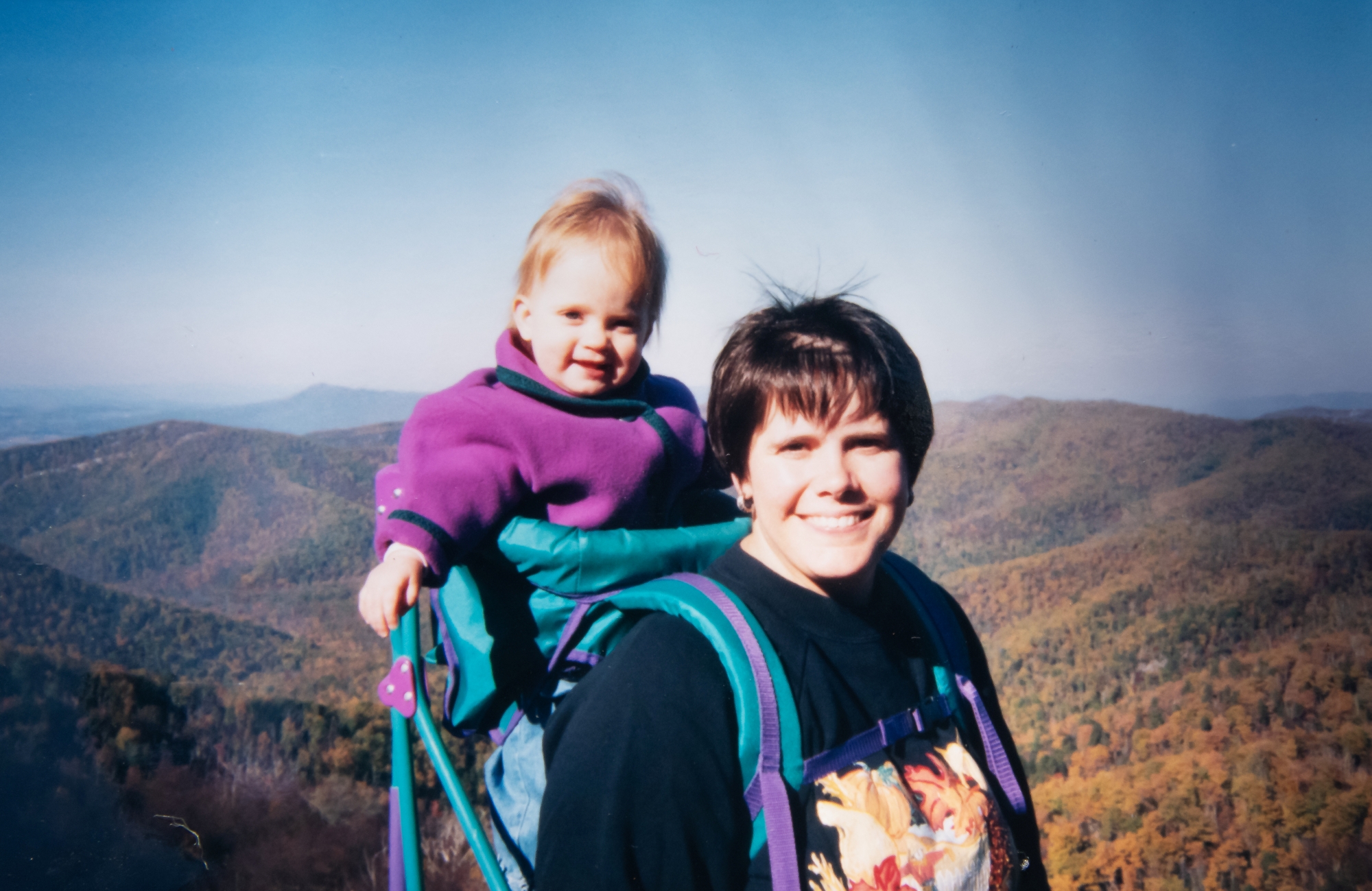 Mom stands with baby in backpack carrier.