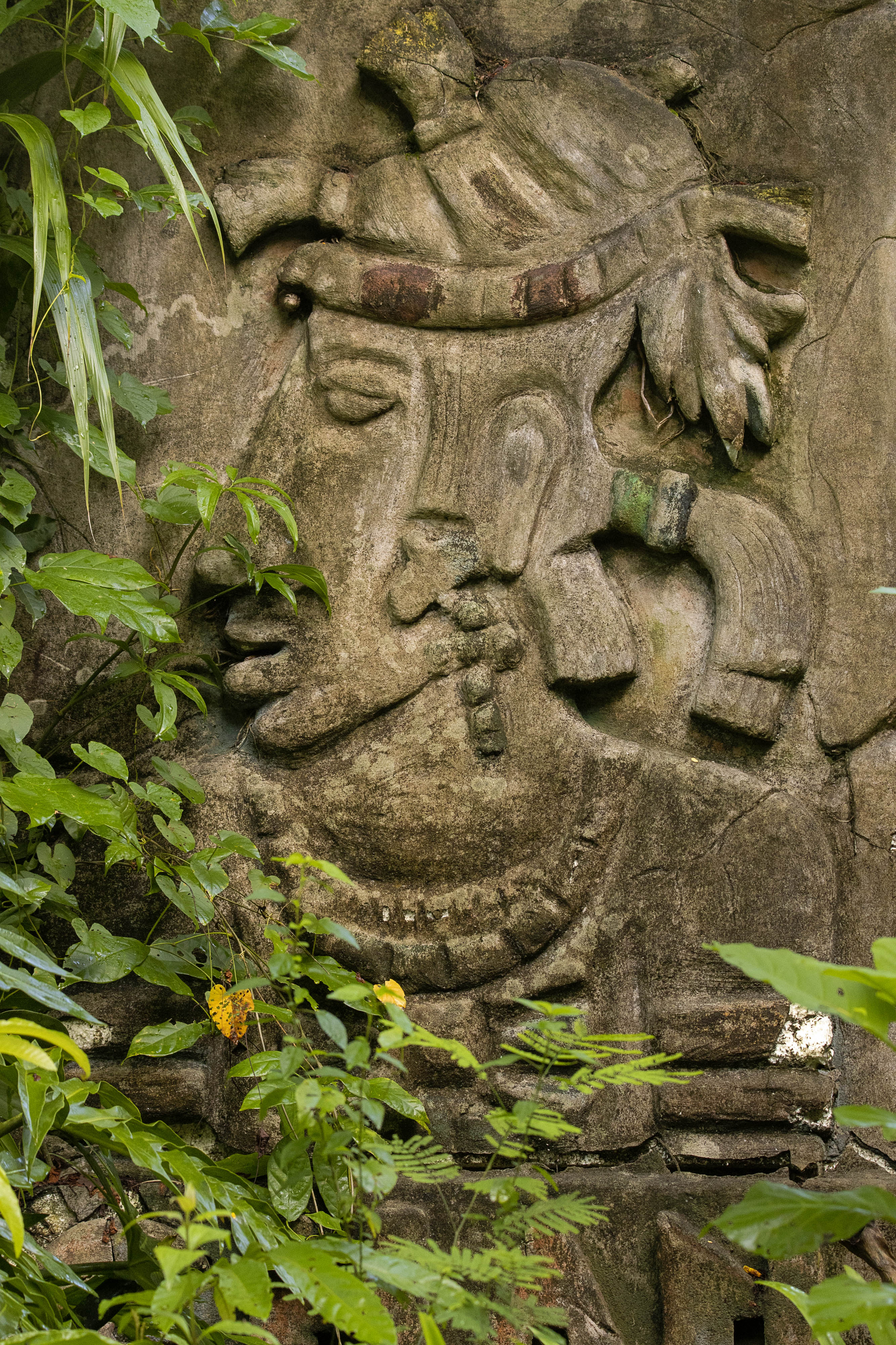 Una escultura tallada se puede ver a través de frondosas ramas.