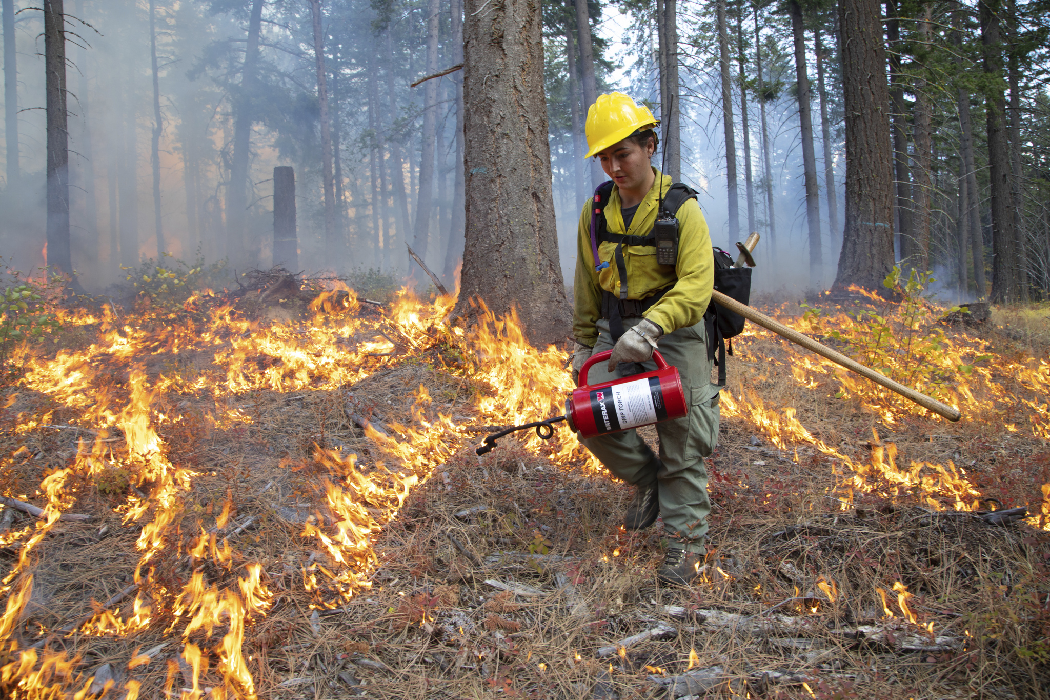 A practitioner in a fire safety suit burns the ground with a torch.