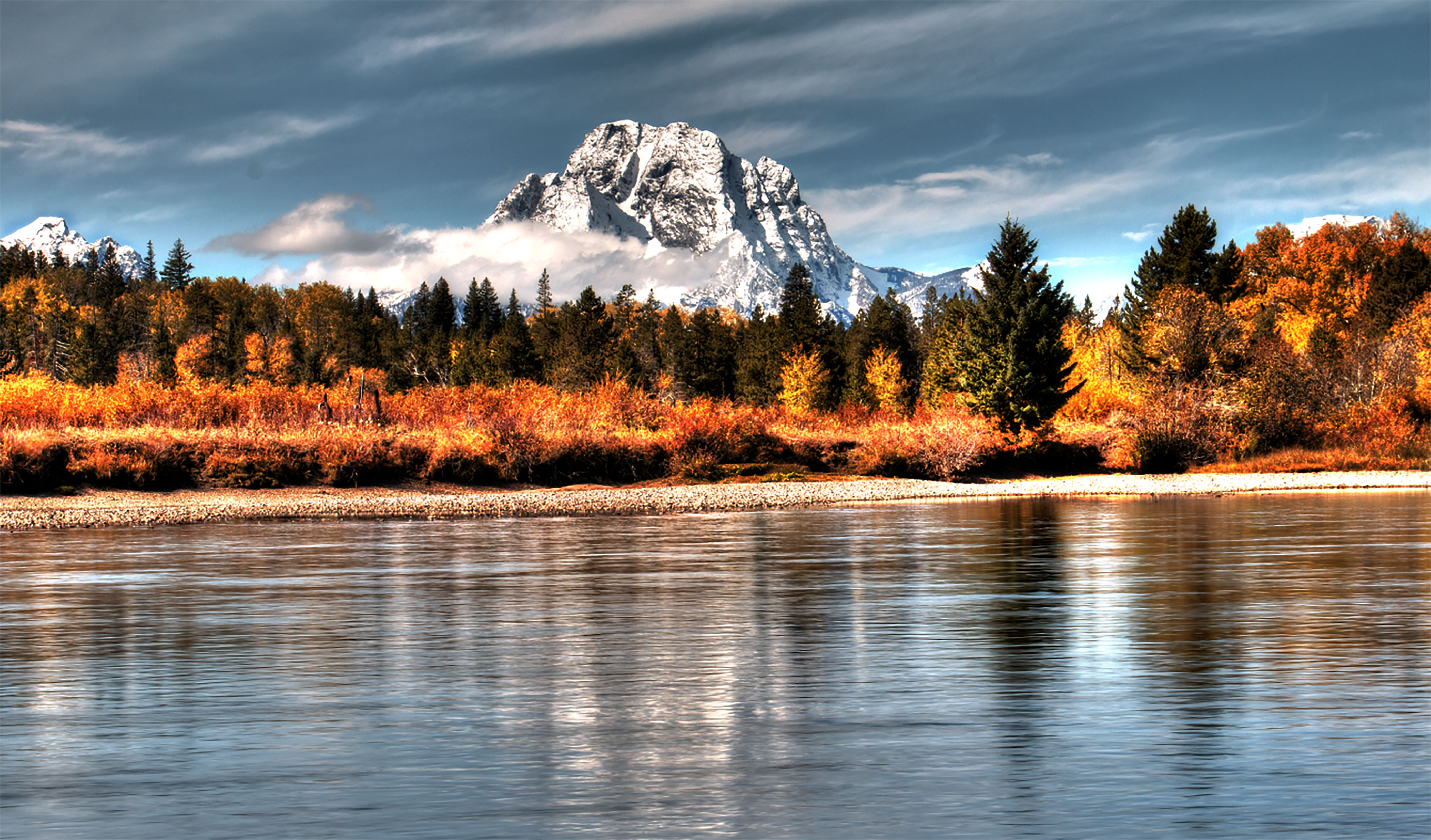 A snow capped mountain is reflected in the surface of the water on Jackson Lake.