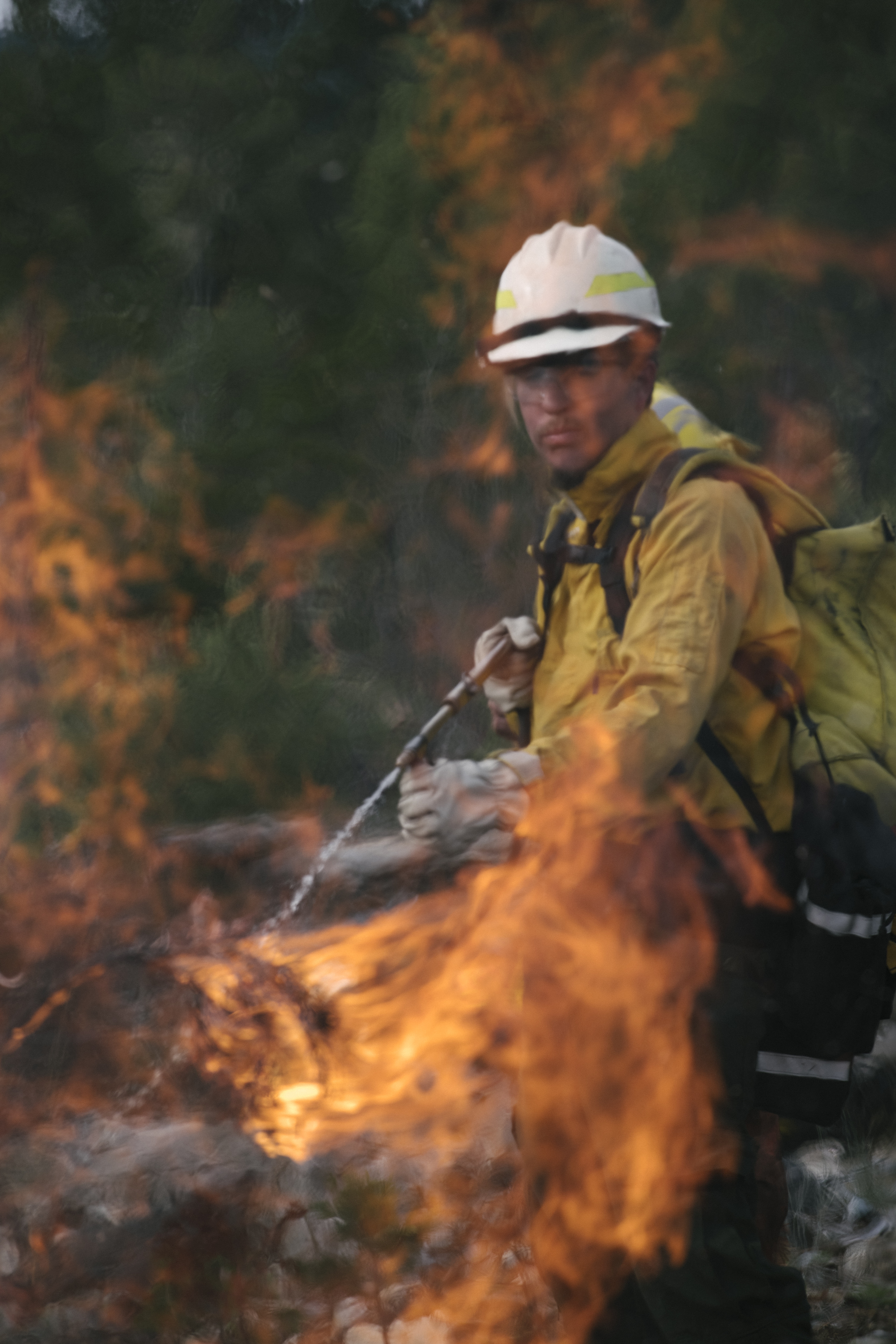 A man in a fire gear uses flame during a controlled burn